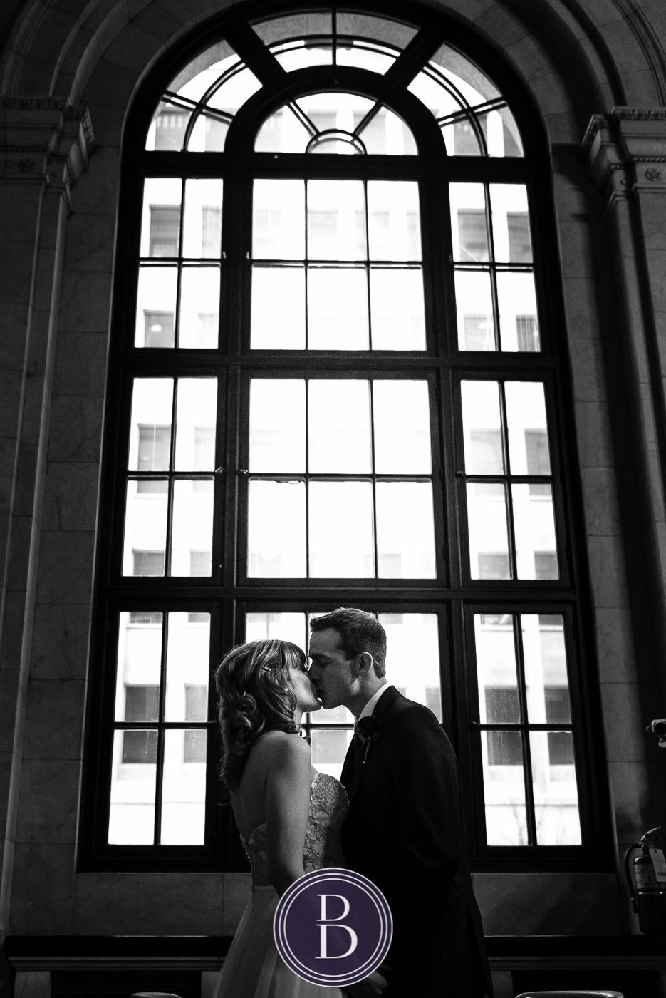 Bride and groom kiss by window