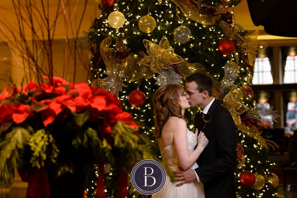 Bride and groom kiss by Christmas tree