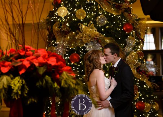 Bride and groom kiss by Christmas tree