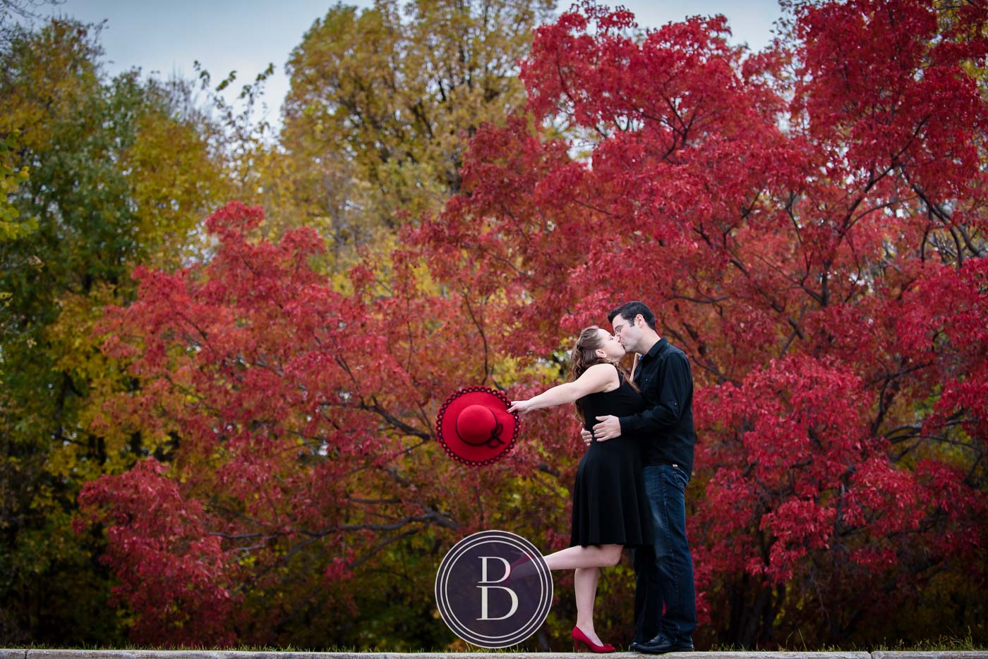 engagement photos kiss with beautiful red trees in the background
