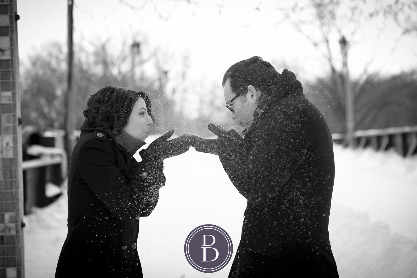 engagement session couple blowing snow into each other