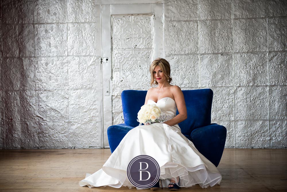 An elegant blue winter wedding in Winnipeg, Manitoba. Wedding portrait of a bride sitting on a blue chair.