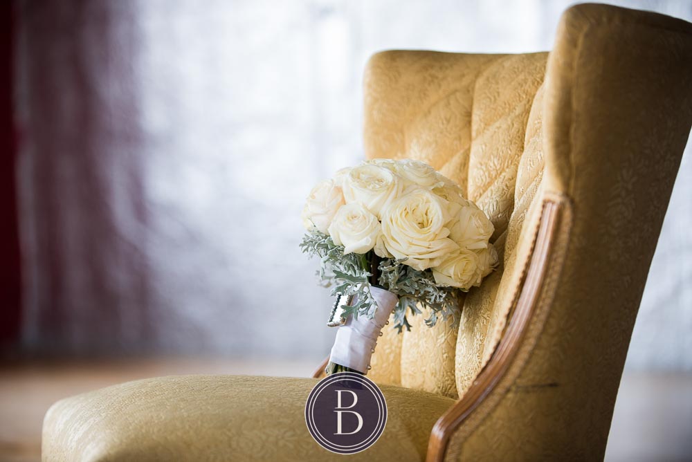 An elegant blue winter wedding in Winnipeg, Manitoba. Bouquet of white flowers on a yellow chair at a studio