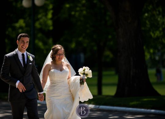 Bride and groom walking and smiling during formal photos Manitoba legislative building in Winnipeg