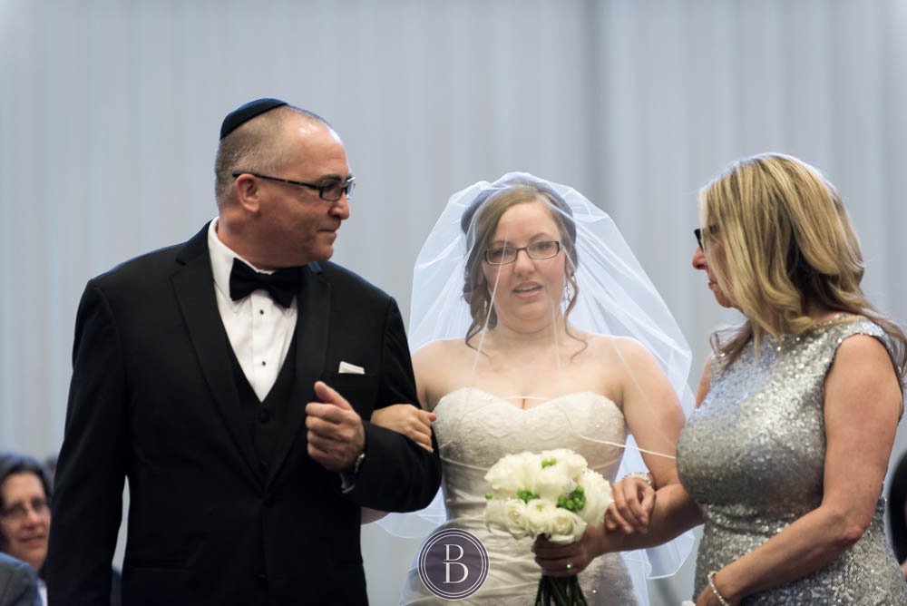 Jewish wedding bride walking down the aisle with parents and seeing groom for the first time