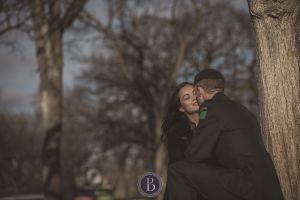 Engaged couple kissing by tree sunset Winnipeg Assiniboine park