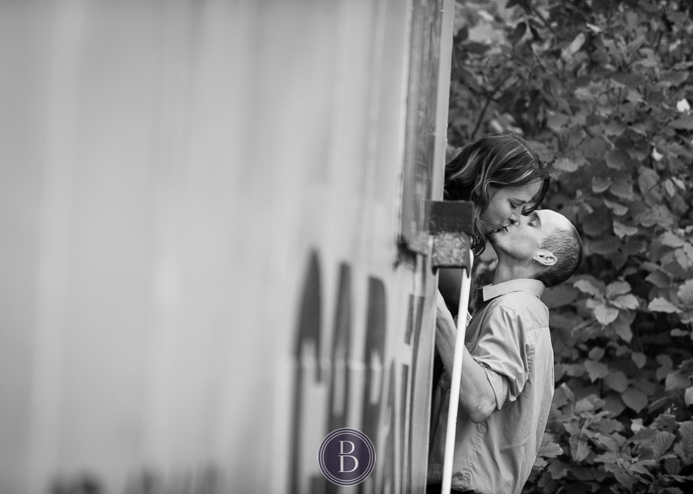 engaged couple kiss by train