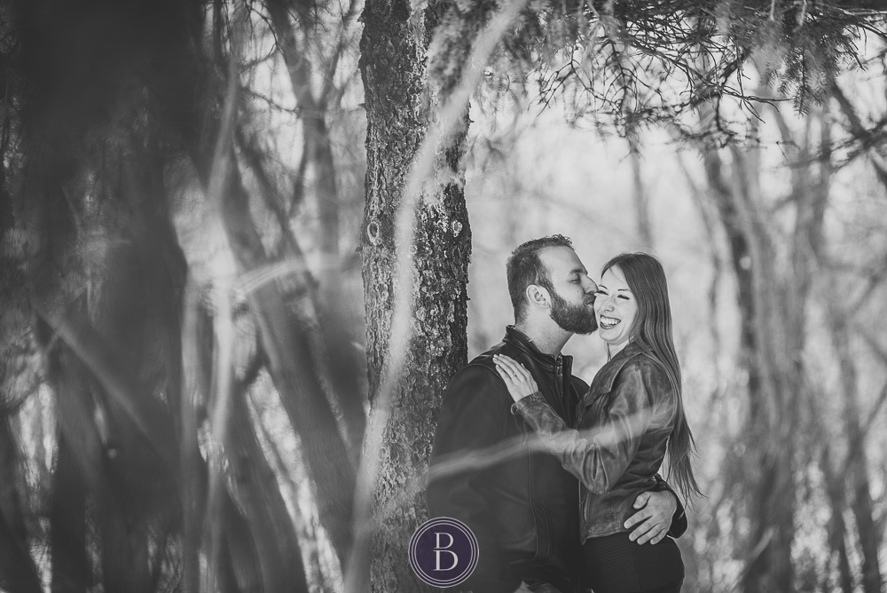 engaged couple smiles kissing in trees