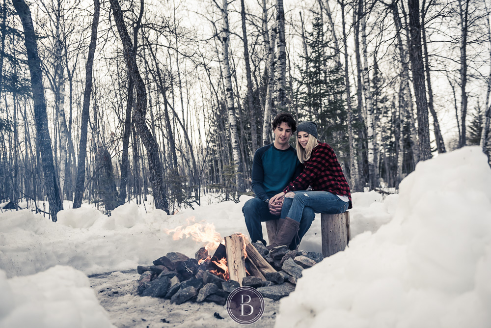 Winter engagement photos couple sitting by fire