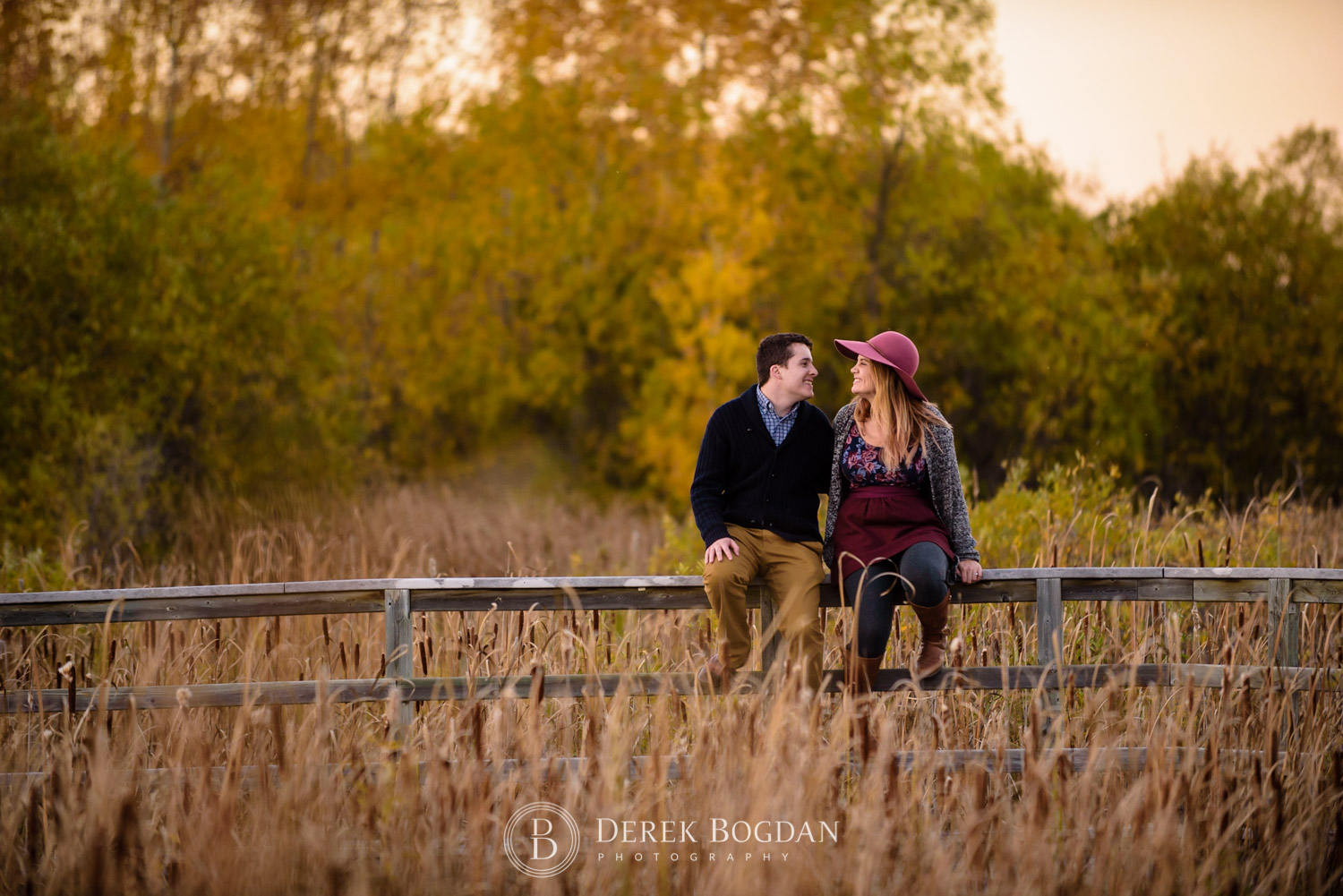 assiniboine forest fall engagement session engaged couple smiling sitting on fence