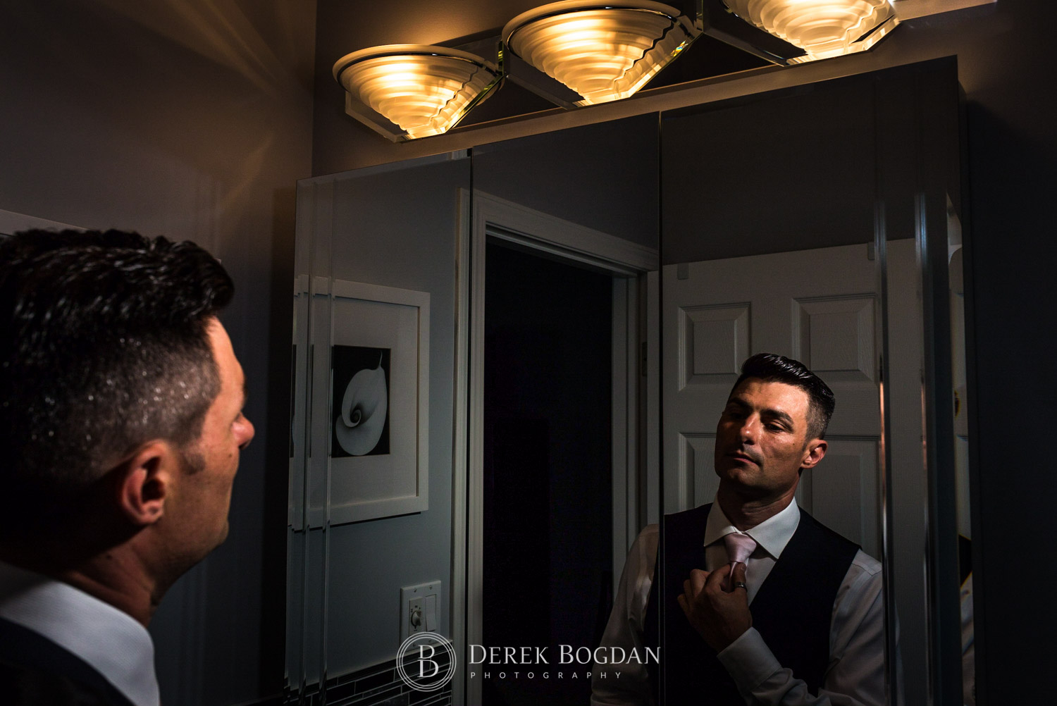 groom getting ready in front mirror before wedding day