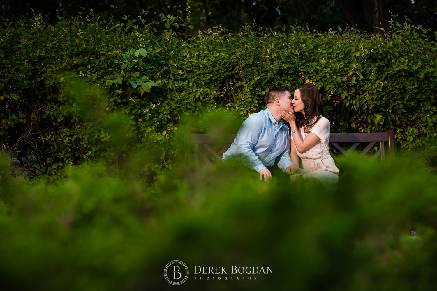 Evening engagement couple kissing on bench at a park