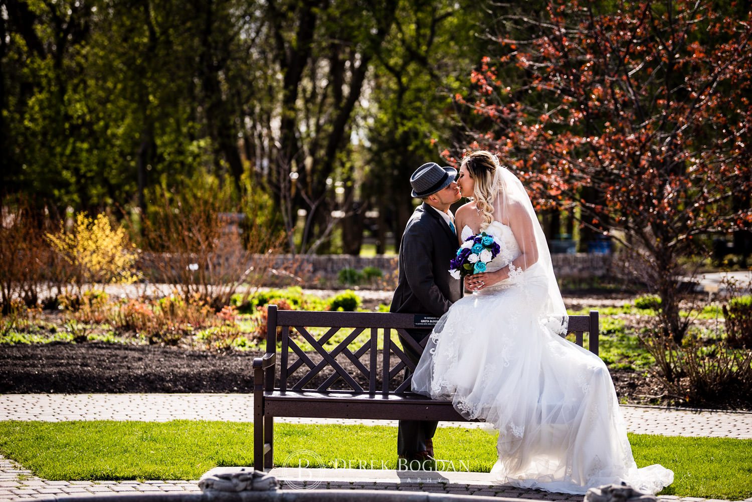 bride groom kiss on bench Winnipeg wedding portrait Assiniboine Park